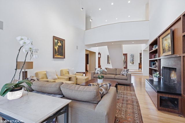 living area with light wood-type flooring, a lit fireplace, and recessed lighting