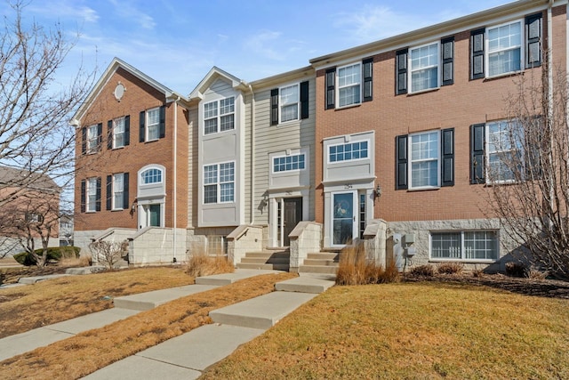 view of property featuring brick siding and a front lawn