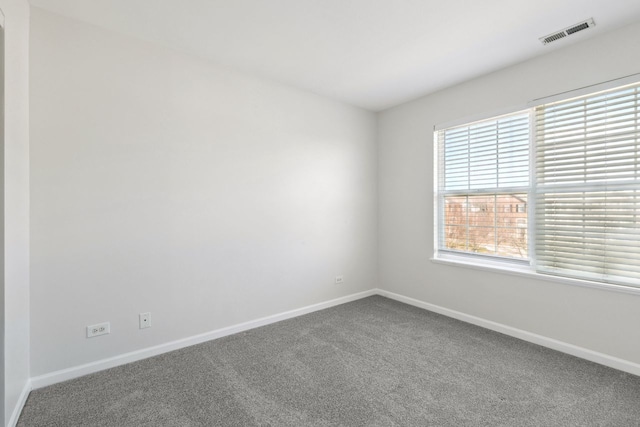 spare room featuring carpet floors, baseboards, and visible vents