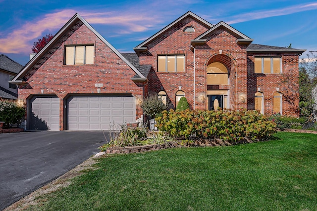 traditional home with a yard, brick siding, and aphalt driveway