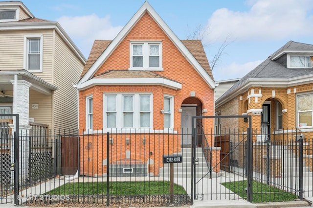 view of front of property featuring roof with shingles, brick siding, a fenced front yard, and a gate