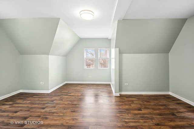 bonus room with dark wood-type flooring, lofted ceiling, and baseboards