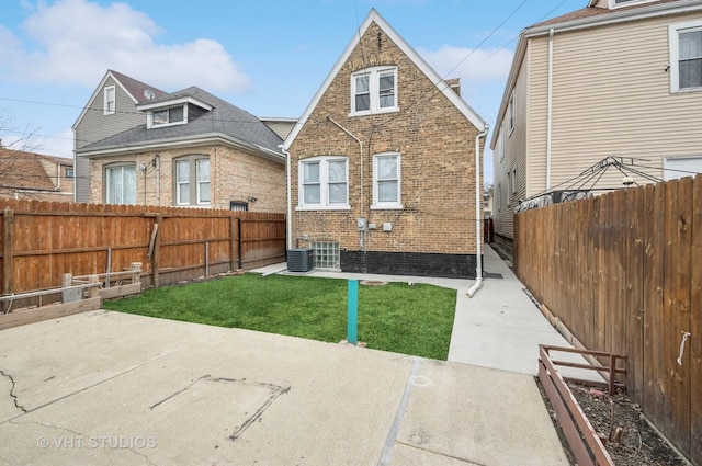 rear view of house with a patio, a fenced backyard, a yard, central AC, and brick siding