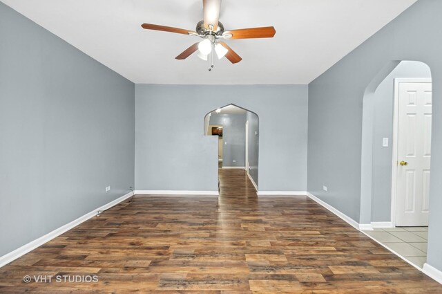 unfurnished room with a ceiling fan, baseboards, arched walkways, and wood finished floors