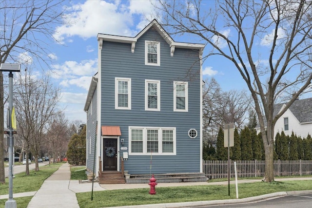 view of front of home with entry steps, fence, and a front lawn