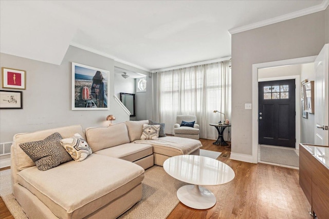 living room featuring crown molding, baseboards, and wood finished floors