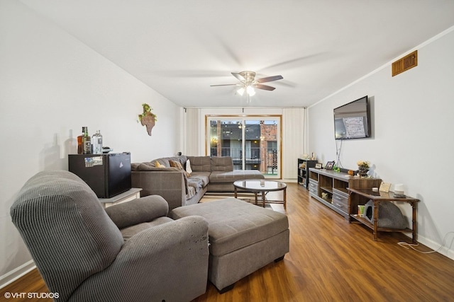 living room with ceiling fan, baseboards, and wood finished floors