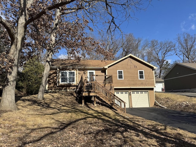 view of front facade featuring a garage, a deck, stairs, and aphalt driveway