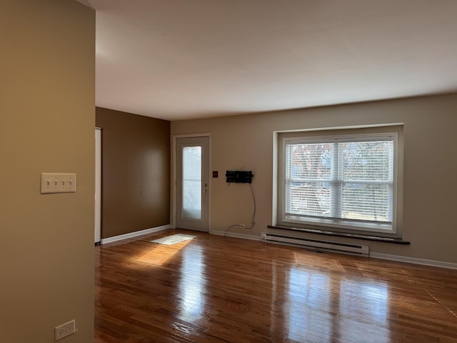 foyer entrance featuring baseboard heating, wood finished floors, and baseboards