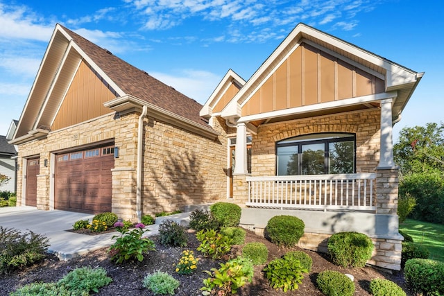 craftsman house featuring concrete driveway, stone siding, an attached garage, a porch, and board and batten siding