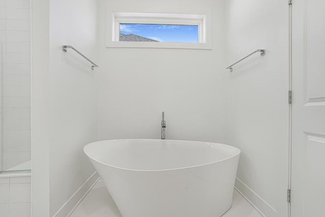 full bathroom featuring a soaking tub, baseboards, and tile patterned floors