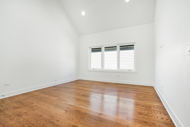 empty room with high vaulted ceiling, baseboards, wood finished floors, and recessed lighting