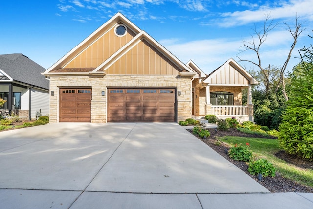 craftsman house with a porch, an attached garage, board and batten siding, stone siding, and driveway