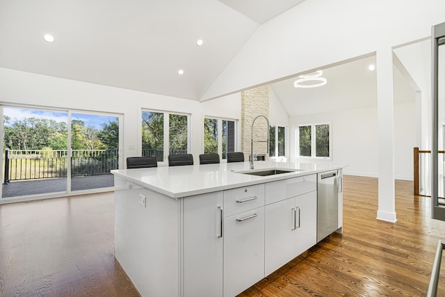 kitchen with wood finished floors, a sink, light countertops, dishwasher, and an island with sink