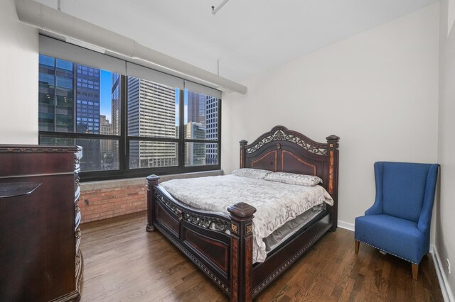 bedroom with baseboards, a city view, and wood finished floors