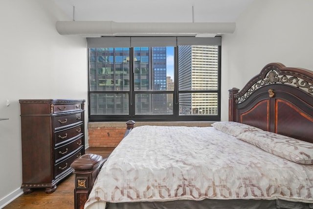 bedroom featuring a view of city, wood finished floors, and baseboards