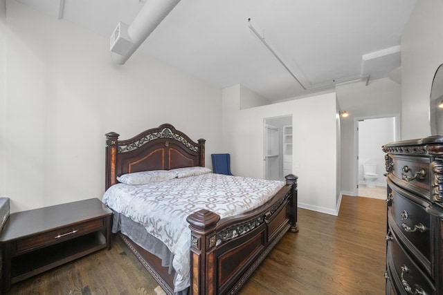 bedroom with attic access, baseboards, a walk in closet, and wood finished floors