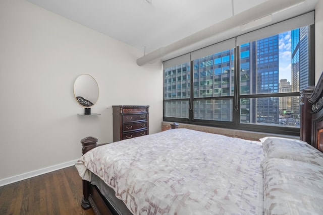 bedroom featuring a view of city, baseboards, and wood finished floors