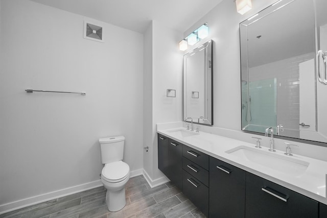 full bathroom featuring double vanity, a sink, toilet, and baseboards