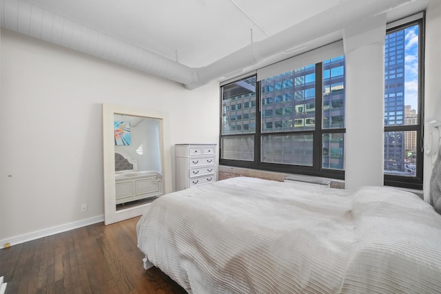 bedroom featuring a view of city, baseboards, and wood finished floors