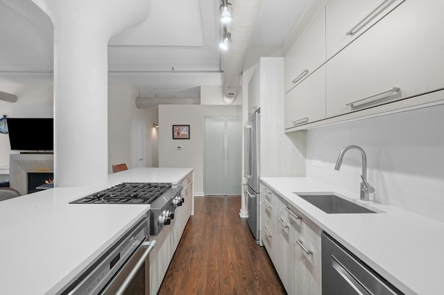 kitchen with stainless steel appliances, modern cabinets, a sink, and light countertops