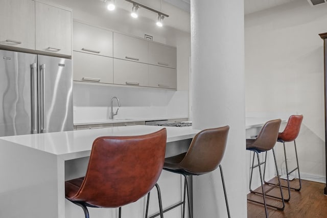 kitchen with dark wood finished floors, a breakfast bar area, light countertops, a sink, and modern cabinets