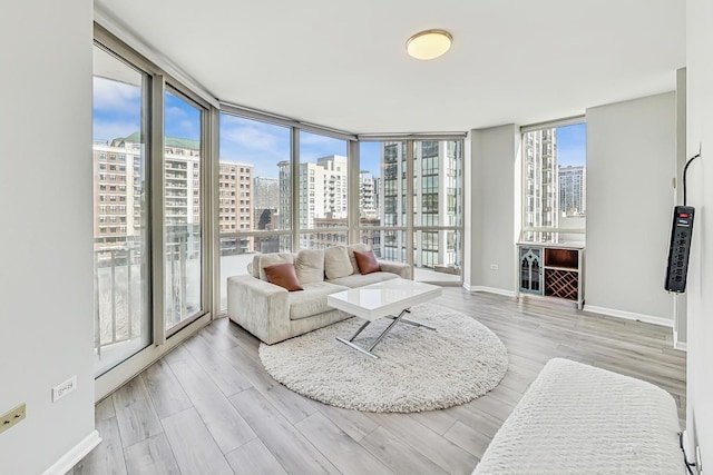 interior space with expansive windows, plenty of natural light, a view of city, and wood finished floors