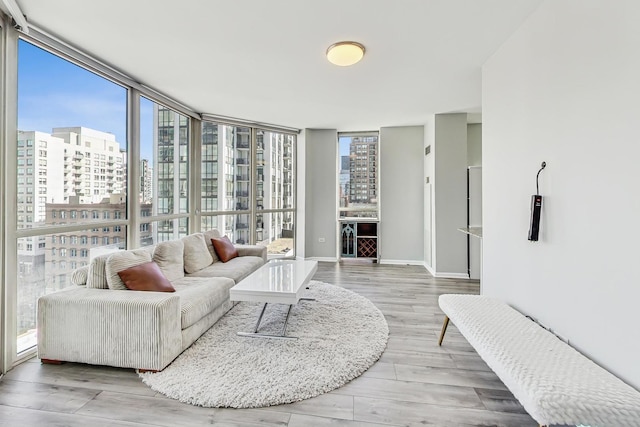 living area featuring expansive windows, a city view, wood finished floors, and a healthy amount of sunlight