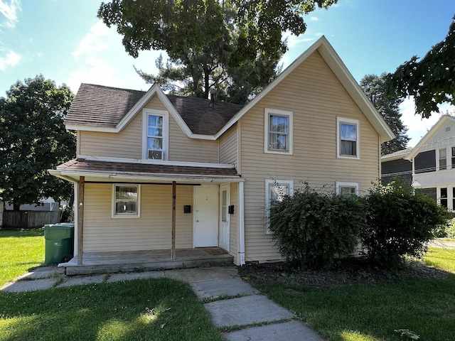 view of front of property with a porch, fence, and a front lawn