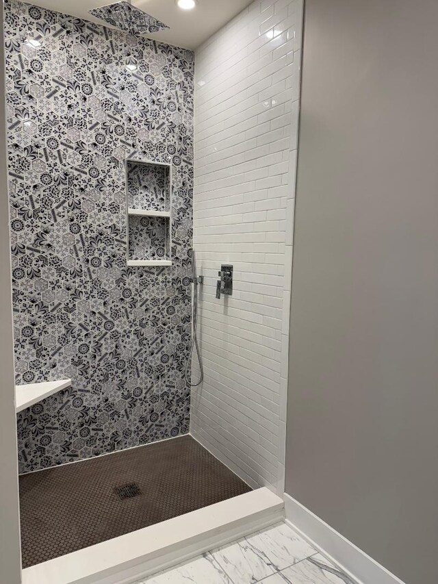 bathroom with baseboards, marble finish floor, and tiled shower