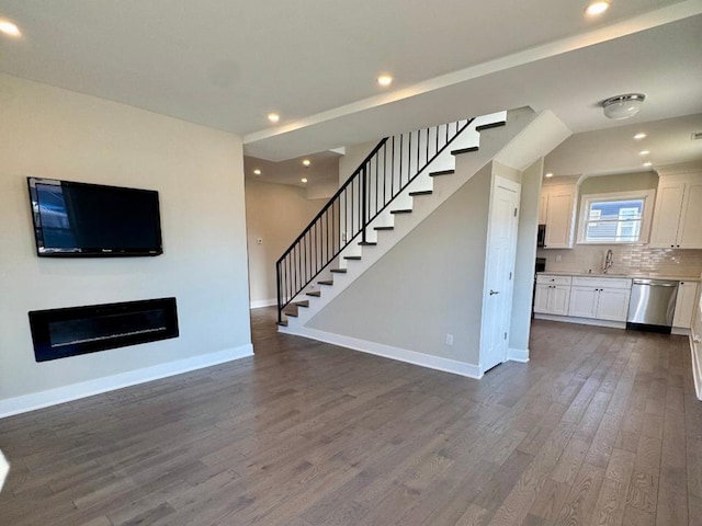 unfurnished living room with stairway, recessed lighting, dark wood-type flooring, and baseboards