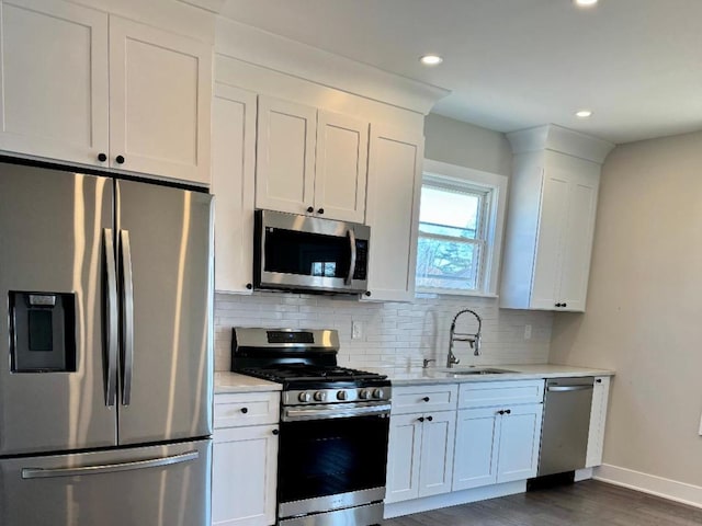 kitchen with a sink, stainless steel appliances, white cabinets, and decorative backsplash