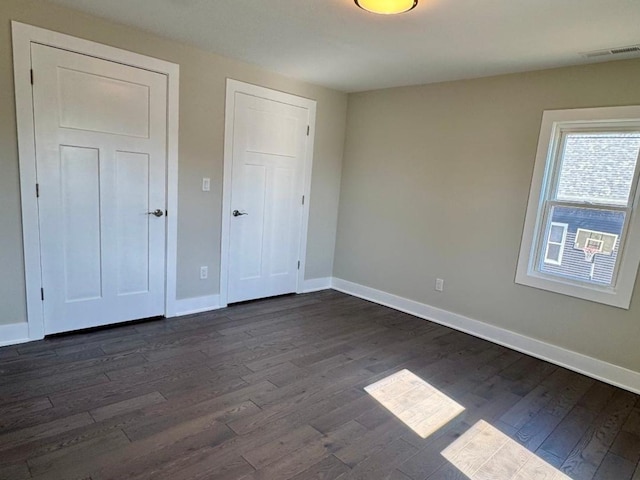 unfurnished bedroom with visible vents, baseboards, and dark wood finished floors