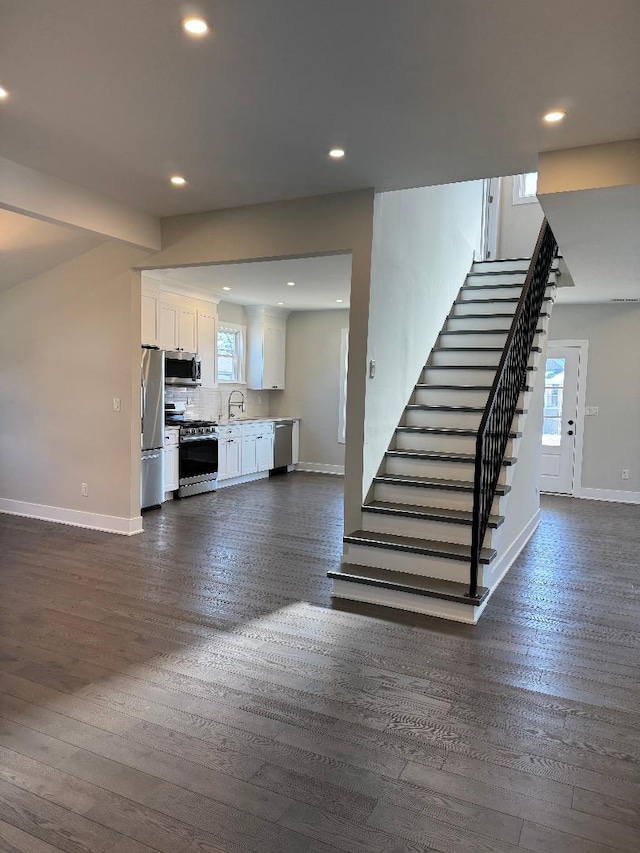 unfurnished living room featuring stairway, recessed lighting, and baseboards