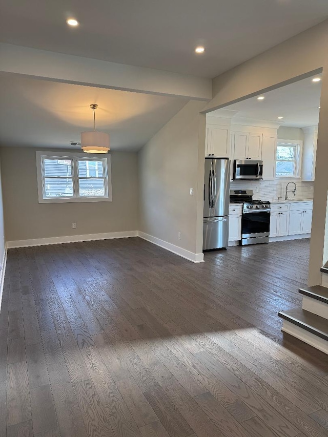 kitchen with a sink, stainless steel appliances, white cabinets, decorative backsplash, and baseboards