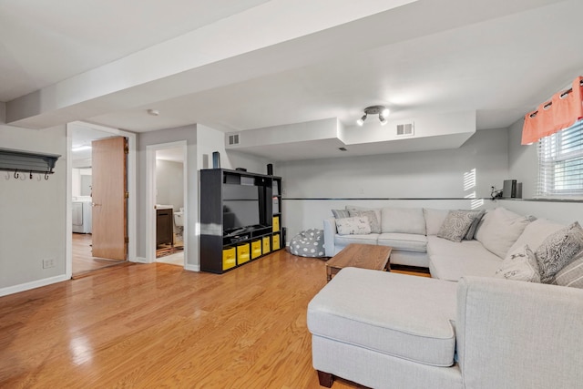 living area featuring light wood-type flooring, baseboards, visible vents, and washer / clothes dryer