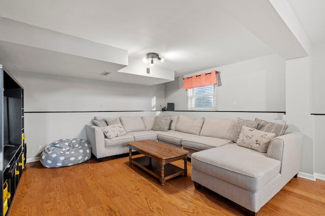 living room with light wood-type flooring, visible vents, and baseboards