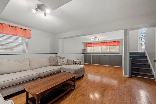 living area featuring a wealth of natural light, stairs, and wood finished floors