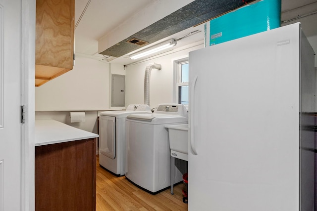 washroom featuring laundry area, light wood-type flooring, electric panel, and washer and dryer