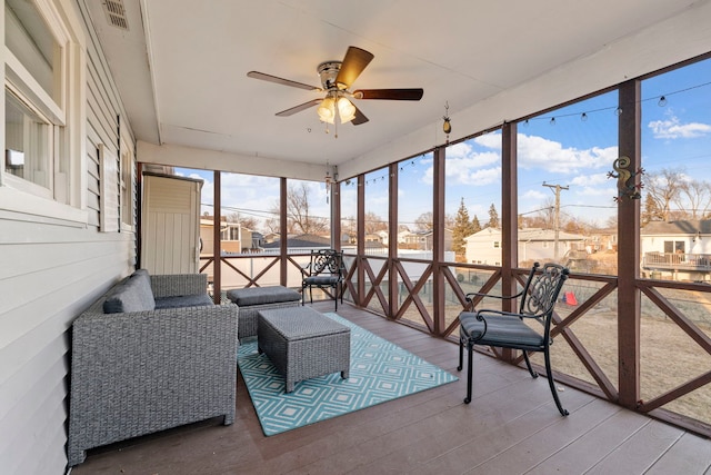 sunroom with a ceiling fan and a residential view