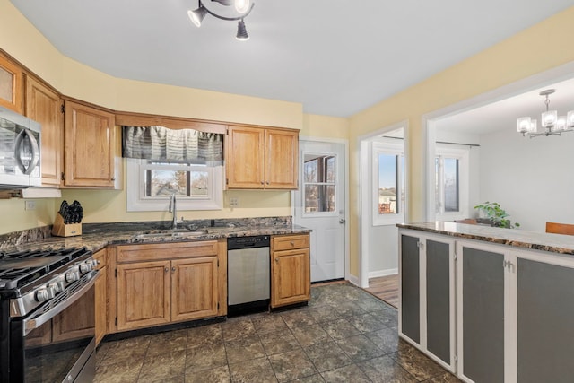 kitchen with dark stone counters, stainless steel appliances, a sink, and baseboards