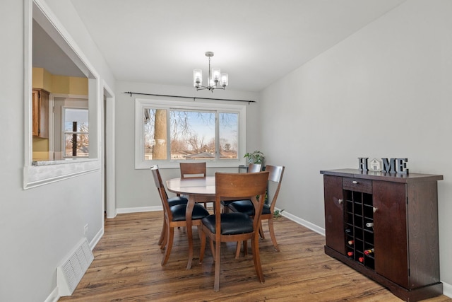 dining room with baseboards, visible vents, a chandelier, and wood finished floors