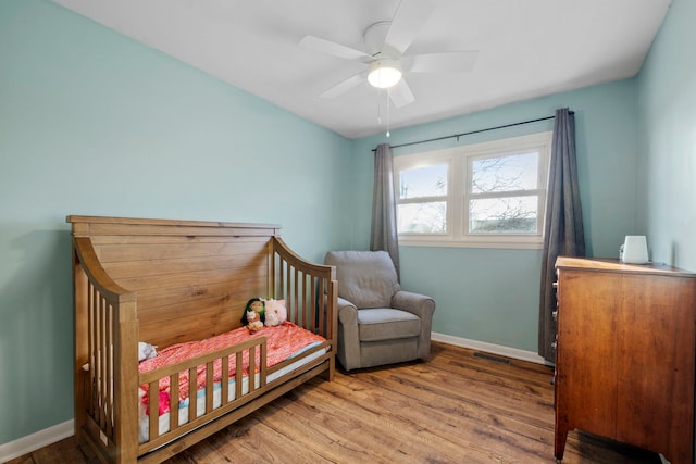 bedroom featuring visible vents, ceiling fan, baseboards, and wood finished floors