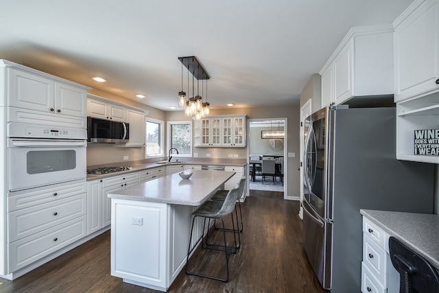kitchen featuring white cabinets, appliances with stainless steel finishes, a notable chandelier, and glass insert cabinets