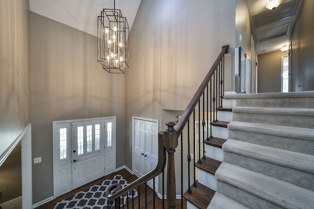 entryway with stairs, baseboards, wood finished floors, and a towering ceiling