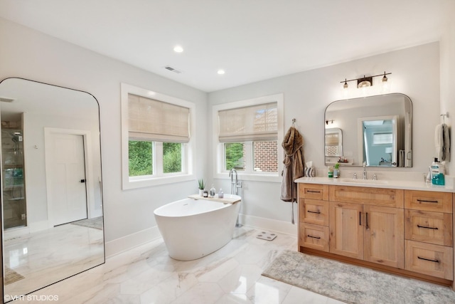 bathroom featuring marble finish floor, visible vents, a freestanding bath, vanity, and baseboards