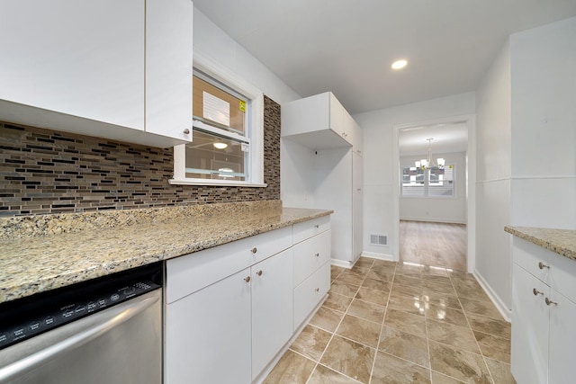 kitchen featuring tasteful backsplash, dishwasher, light stone counters, an inviting chandelier, and white cabinetry