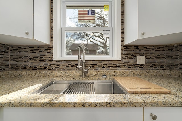 kitchen featuring backsplash, white cabinetry, and a sink