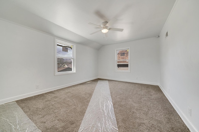 carpeted spare room with visible vents, baseboards, a ceiling fan, and vaulted ceiling