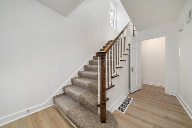 stairway with visible vents, baseboards, and wood finished floors